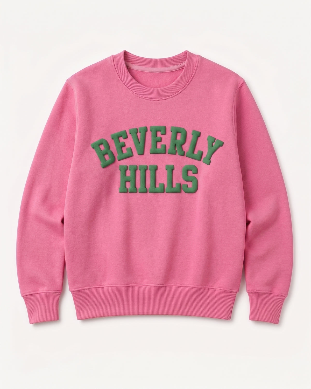 A pink crewneck sweatshirt featuring 'BEVERLY HILLS' printed in green varsity-style block letters across the chest, displayed on a clean off-white background.